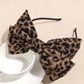 Detailed close-up of a large leopard print bow headband on a white ceramic cup - Leopard Print