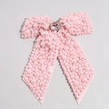 Close-up of pink pearl bow hair clip with central rectangular gemstone and rhinestones - Pink