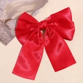 Detail of red double-layered satin bow hair clip on premium beige textured leather background - Red