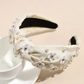 Close-up of beige knotted headband with elegant white pearls and floral ornaments - Milk Yellow