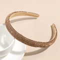 Close-up of champagne brown headband with shimmering rhinestones on a white cup - Gold