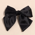 Dettaglio dell'elegante grande fiocco per capelli in raso nero con trama liscia e lucida - Nero