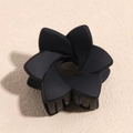 Dettaglio di un fermaglio per capelli nero opaco a forma di fiore su sfondo beige - Fiore a Spirale Nero Opaco
