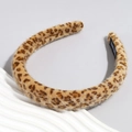 Detalle de la diadema de felpa con estampado de leopardo mostrando la textura suave y la etiqueta artesanal - Leopardo Amarillo