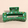 Detail showing Christmas themed green rectangular claw clip with festive prints - Green