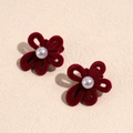 Detalle de pinzas de flores de terciopelo rojo con perla central sobre fondo beige - Pareja de Flores Rojas con Perlas