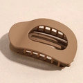 Primer plano de la pinza para el pelo marrón mate con dientes en superficie beige - Caqui