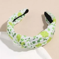 Detailed close-up of a wide knotted headband with green clover patterns on white fabric - Yellow Clover