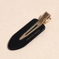 Close-up of a black acetate beak hair clip with gold metal clasp and French lettering - Teardrop Black
