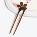 Macro detail of amber tortoiseshell hairpin with flower shape and crystal accent - Amber