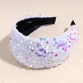 Detail view of wide velvet headband featuring iridescent sequins and black fabric lining - White
