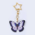 Detail eines Schmetterlingsanhängers aus Acryl mit lilafarbenem Farbverlauf und Goldstern - Violetter Schmetterling