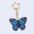 Nahaufnahme von schwarzem Schmetterling-Schlüsselanhänger mit goldenem Sternen-Verschluss - Blauer Schmetterling