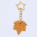 Nahaufnahme von goldenem Stern-Verschluss und bernsteinfarbenem Ahornblatt-Anhänger - Gelbes Ahornblatt