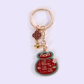 Makroaufnahme roter Glücksbeutel-Schlüsselanhänger mit Goldbarren und Emaille-Anhängern - Voller Glück Ring