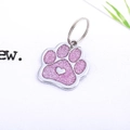 Detail of paw-shaped metal pet ID tag with pink glitter finish and silver heart charm - 23*27mm / Light Pink