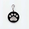 Macro view of a circular metal pet tag with a rhinestone paw print and lobster clasp - Claw Print / Black