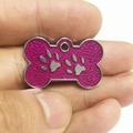 Rosaroter glitzernder Hundeanhänger in Knochenform mit silbernen Pfotenabdrücken - Fuchsia