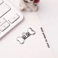 Detail of silver bone-shaped pet tag with black paw prints on a minimalist background - 30*15mm / Black