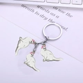 Three white enamel cat charms on a silver alloy keychain over a book and keyboard - 9cm / White Cat