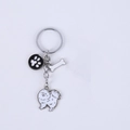 Detail of metal dog keychain featuring white Pomeranian, bone, and paw print pendants - New Pomeranian + Feet