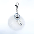 Détail d'un porte-clés à pompon blanc avec pendentifs chien et patte sur anneau argenté - Caniche Blanc