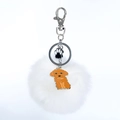 Détail d'un porte-clés pompon blanc avec pendentif patte de chat et fermoir mousqueton - Caniche Jaune