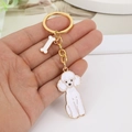 Golden poodle keychain with white enamel dog and bone pendant held in hand - With Bone Charm / White Poodle Gold