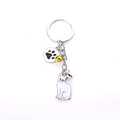 Cat keychain with white kitty charm, yellow bell, and black paw print on silver metal - Tailless White Cat