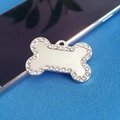 Macro shot of silver bone-shaped pet ID tag with rhinestones on blue knit background - 34 Rhinestones White
