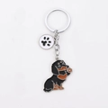 Cartoon black and tan Dachshund metal keychain with a white paw print pendant charm - Black Waving Dachshund With Paw