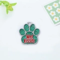 Detail view of a paw-shaped metal pet tag with green glitter and Wet Kisser engraving - Green