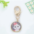 Gros plan d'un pendentif doré avec illustration de chat et fermoir mousqueton en cœur - Chat à Fleurs Rouges Rond