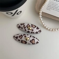 Dettaglio di fermagli per capelli leopardati con cuori dorati su sfondo color crema - Coppia / Marrone