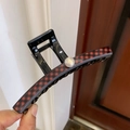 Detail view of large checkered hair claw clip with pearl accent on polished black finish - Black Red Plaid