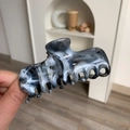 Dettaglio ravvicinato di una pinza per capelli in acetato con motivo marmoreo - Texture Marmo Grigio