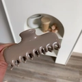 Close-up of a large brown acetate hair claw clip with a glossy finish for hair styling - Gray