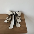 Close-up of elegant cream bow hair claw clip with black piping on rustic wooden table - White