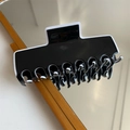 Vista dettagliata della grande clip per capelli bianca e nera riflessa su uno specchio - Pinza per Capelli Quadrata Nera