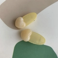 Close-up of pastel yellow heart-shaped jelly hair clips on a geometric background - Yellow