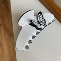 Macro shot of white resin hair clip with elegant black butterfly decorative outline - White Butterfly Claw Clip