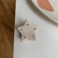 Close-up of star-shaped beige resin hair claw clip with rhinestones and lar lettering - Beige Star