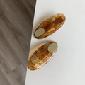 Detail showing a pair of tortoise shell oval hair clips with gold metal plates on a white desk - Caramel color