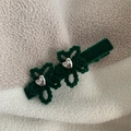 Dettaglio macro di un fermaglio per capelli in velluto verde scuro con cuori di strass - Verde