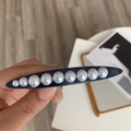 Dettaglio di fermaglio blu marino con perle bianche sfumate e scritte in oro eleganti - Clip a molla / Blu Aerodinamico