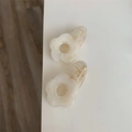 Macro shot of two floral acrylic hair clips featuring white marble texture and hollow centers - Off White