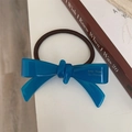 Primo piano di un elastico per capelli con fiocco in acetato blu e scritta artigianale - Blu