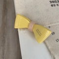 Détail d'une pince à cheveux nœud jaune avec lettrage fait main sur fond textile - Jaune Vif