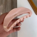 Detailed macro view of the handmade pink crescent moon acetate hair claw with gold logo - Light Pink
