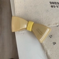 Gros plan sur la pince à cheveux nœud crème fait main avec inscription Amy Bear - Jaune Foncé